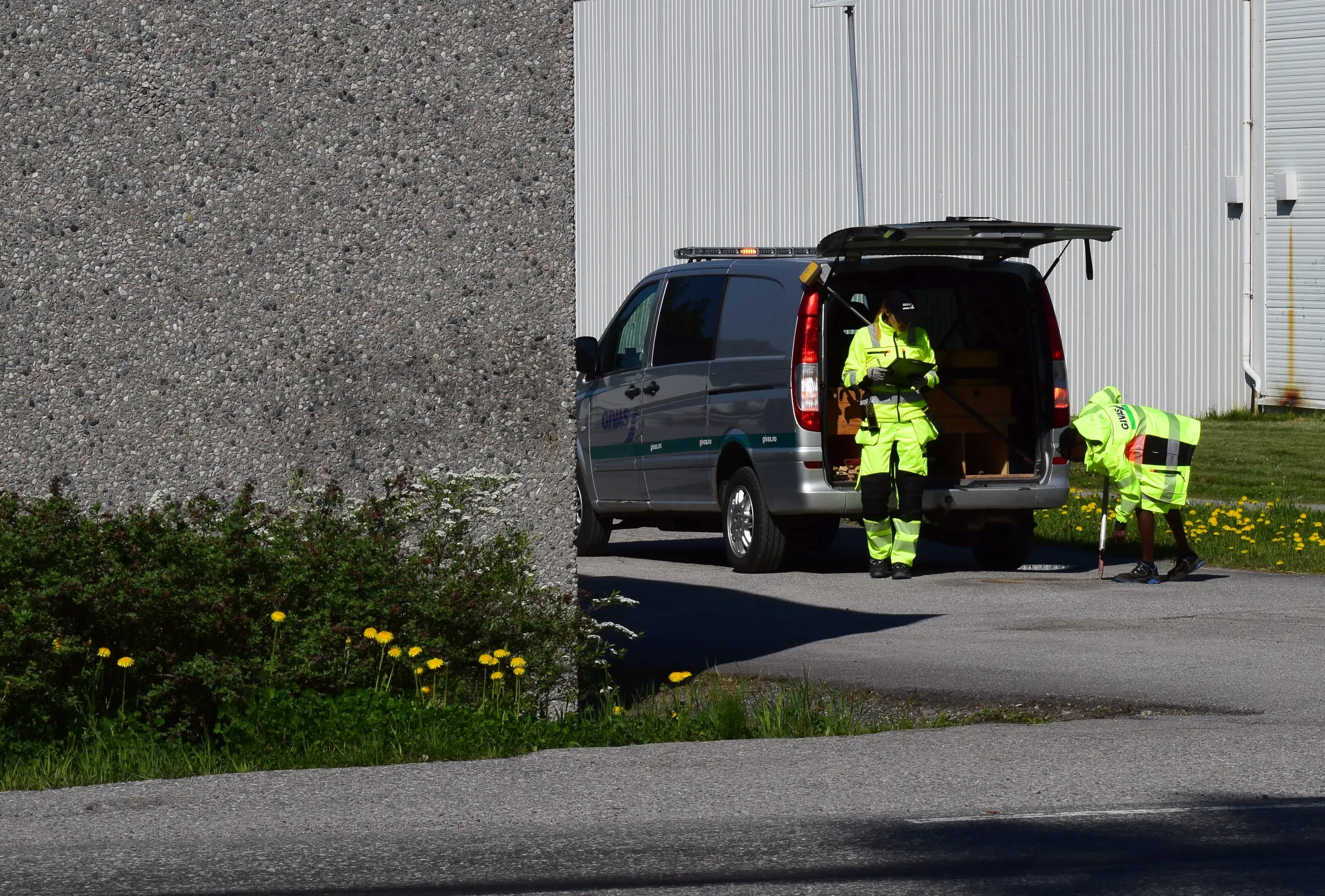 Workers in hi-vis vests loading equipment into the back of a van