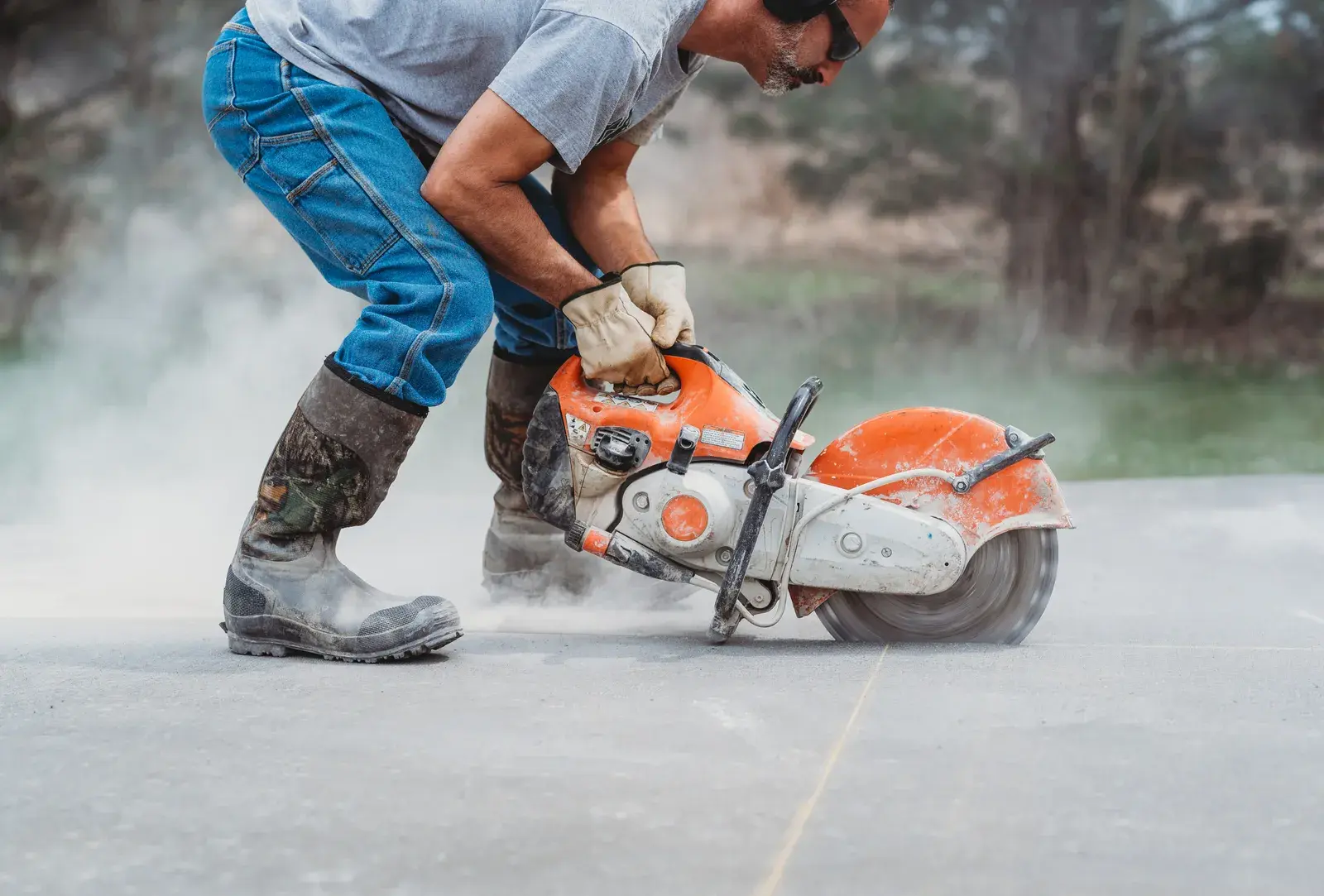 Tradesperson cutting concrete with power tool